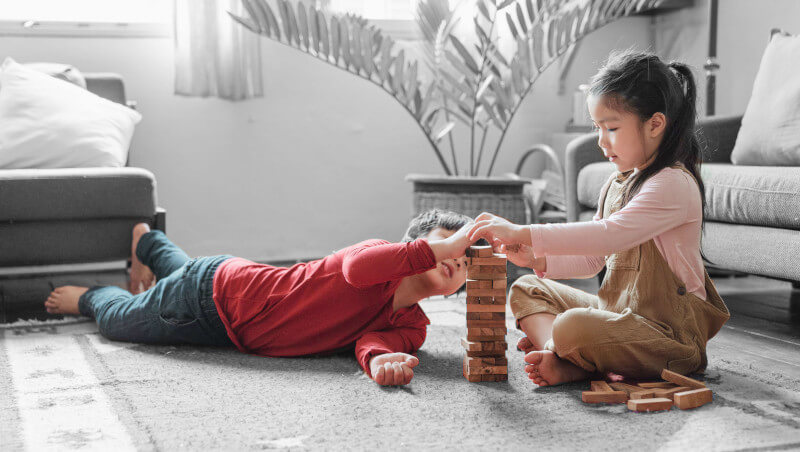 deux enfants assis avec des jouets en bois de construction