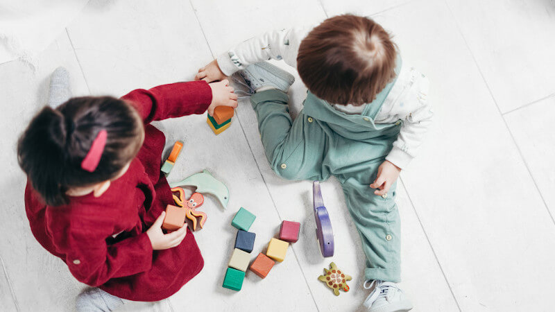 deux enfants qui jouent avec un jeu en bois de cubes de construction