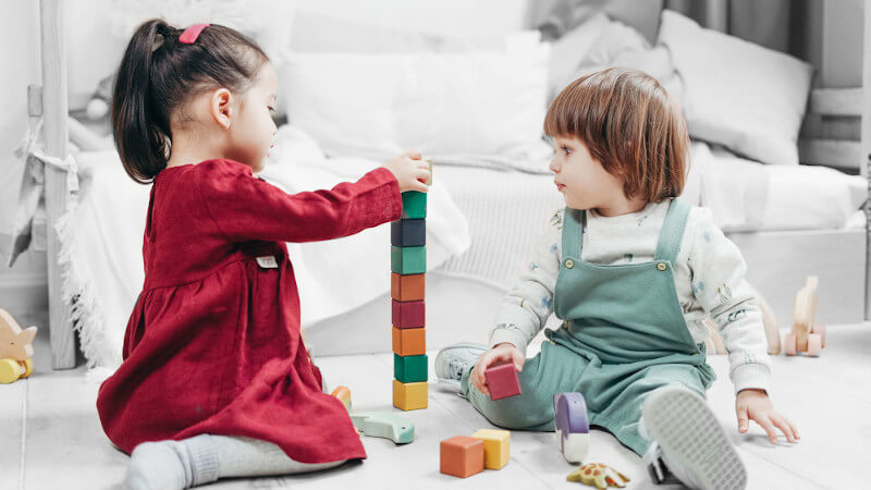 deux jeunes filles construisant une tour avec des cubes en bois