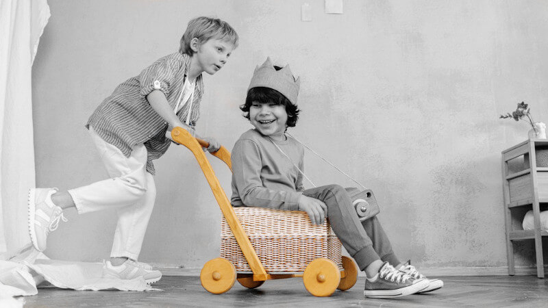 deux jeunes garçons jouant avec un pousseur chariot de marche bébé en bois