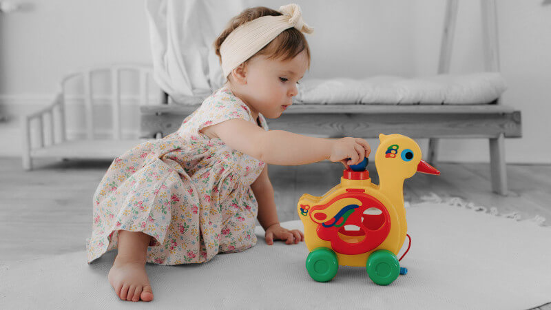 ein Baby mit einem nachziehspielzeug in form einer ente