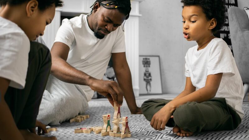 trois enfants jouant avec des jouets montessori en bois de type jeux coopératifs