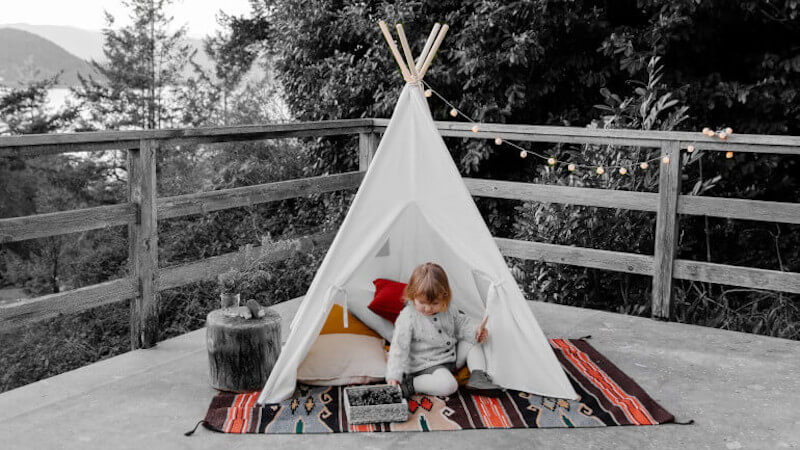 un bébé assis dans un tipi de jeu pour enfant