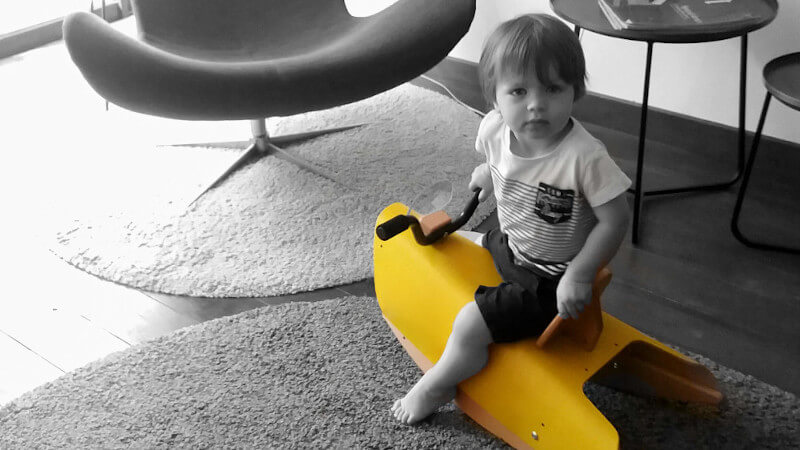 un bebe assis sur un jouet a bascule de couleur jaune