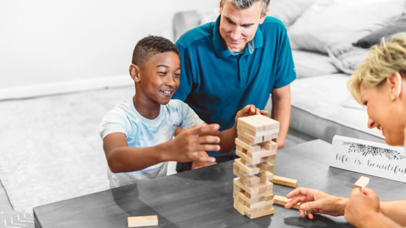 un enfant avec jouets en bois et avec ses parents