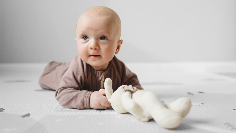 un enfant allongé au sol avec un doudou bebe