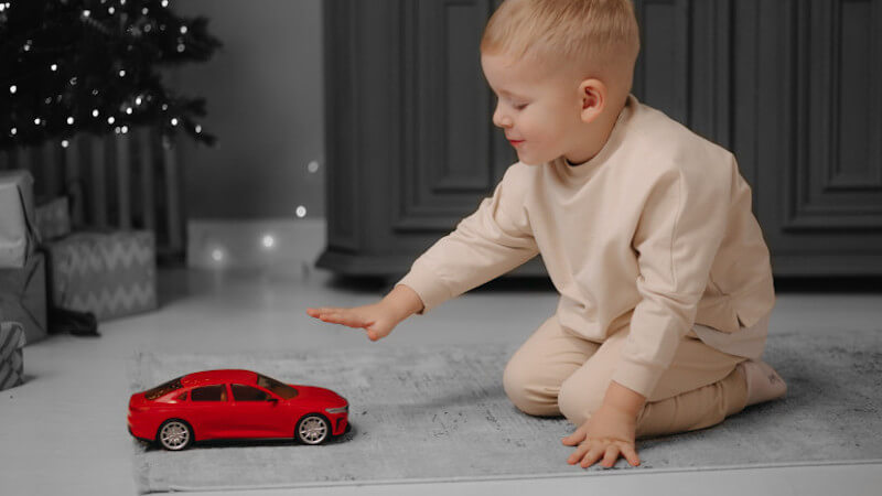 un enfant qui joue avec une voiture miniature de couleur rouge