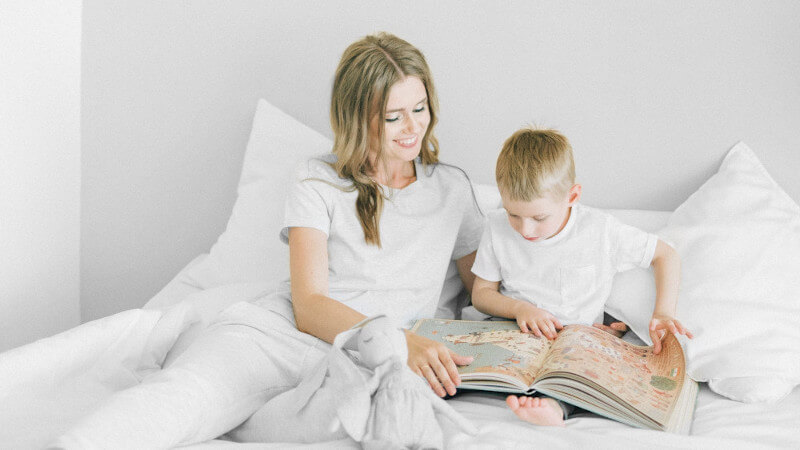 un enfant qui lit un livre d'éveil avec sa maman
