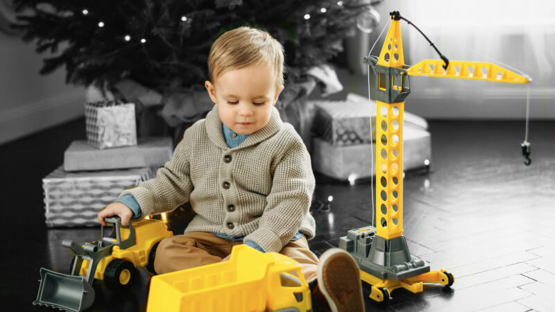 un jeune garçon avec des jouets miniatures camion et tracteur