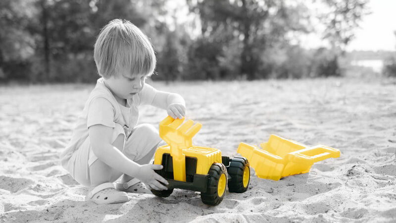 un jeune garçon avec des jouets camion miniature en plastique