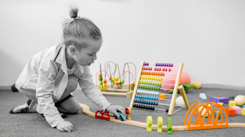 un niño jugando con un tren de madera en miniatura