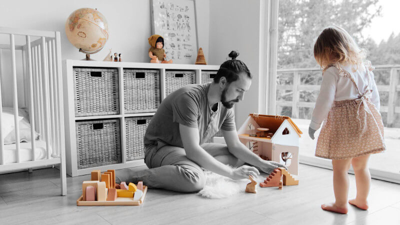 un papa avec sa fillette jouant avec des jouets en bois
