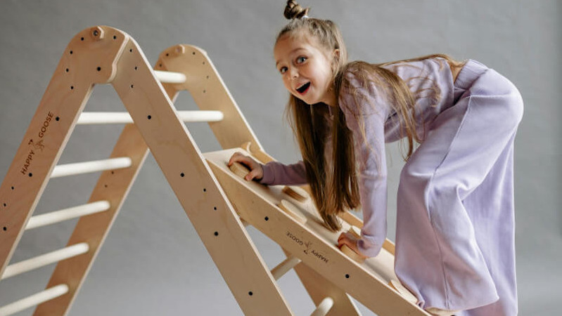 une enfant jouant sur un jouet triangle de Pikler