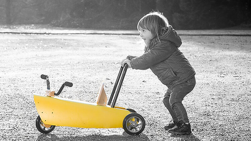 une fillette avec un jouet chariot de marche bébé en bois