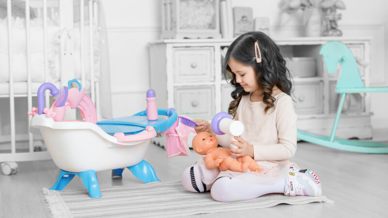 une fillette avec des jouets poupée et berceau