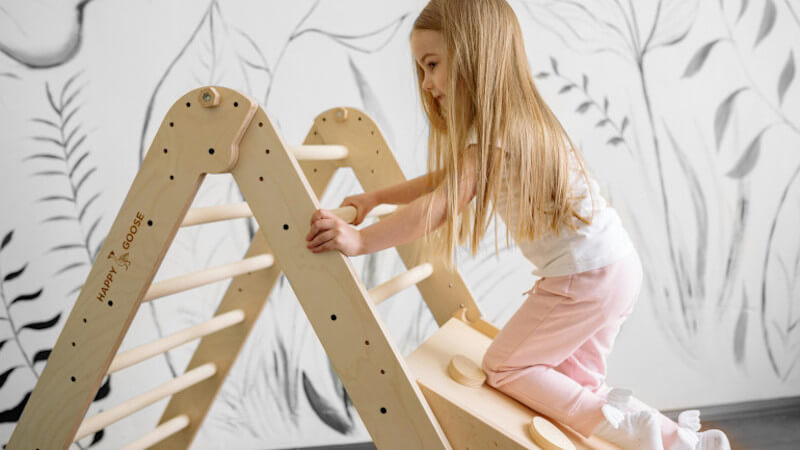 une fillette jouant sur un triangle Pikler