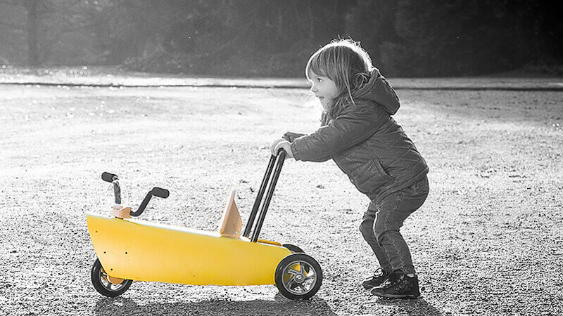 une fillette poussant un jouet chariot de marche bébé en bois jaune