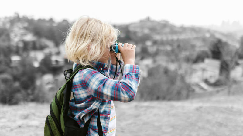 une garçon regardant le paysage avec des jumelles