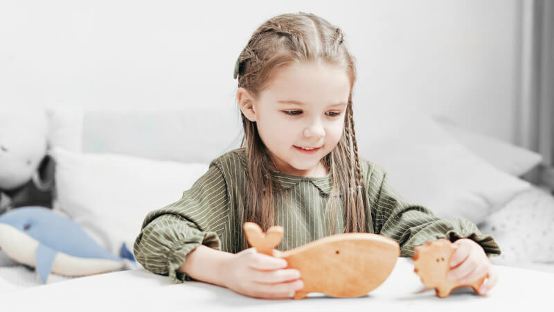 une petite fille qui joue avec des jouets en bois